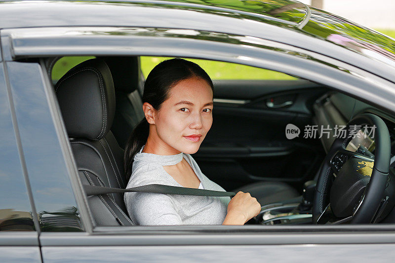 一个年轻的亚洲妇女在一辆车里用安全带的肖像。