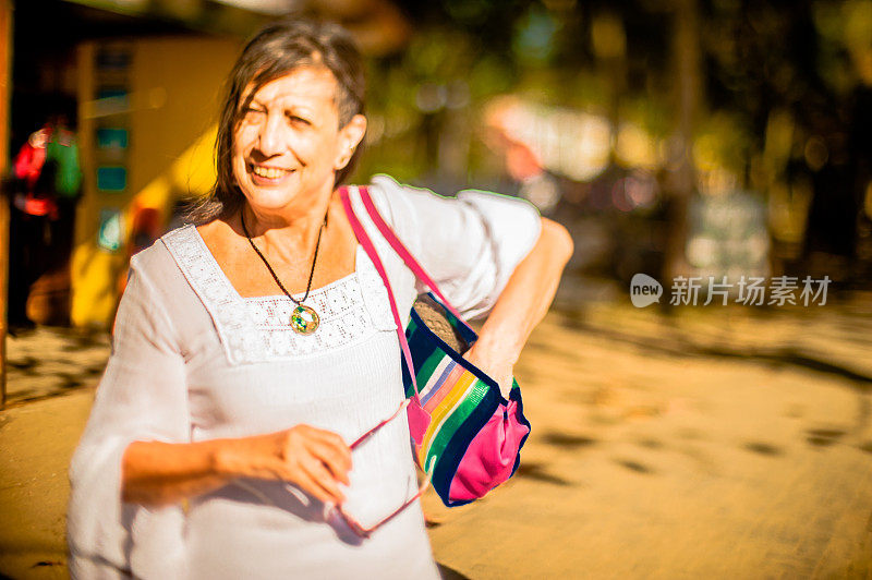 中年妇女摆姿势的肖像户外，举着老花镜，bosa与把手，阳光明媚的日子，选择性聚焦，模糊的背景