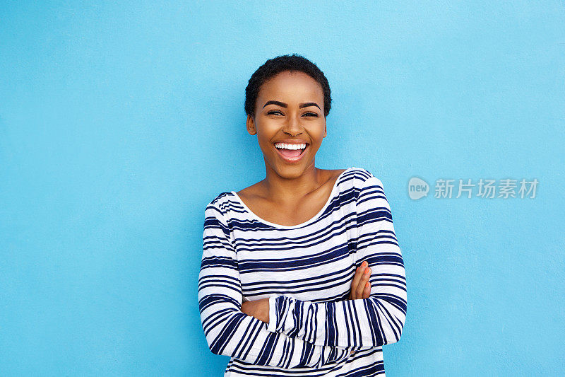 快乐的年轻黑人妇女对着蓝色的墙笑