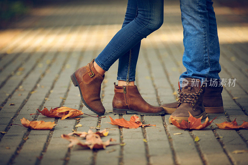 一对浪漫的夫妇在秋天公园的脚的特写。