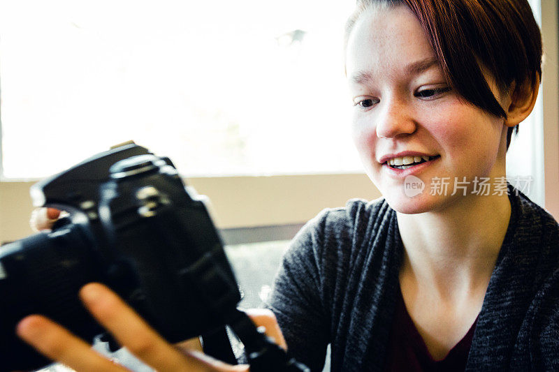 年轻的女摄影师正在展示相机上的图像