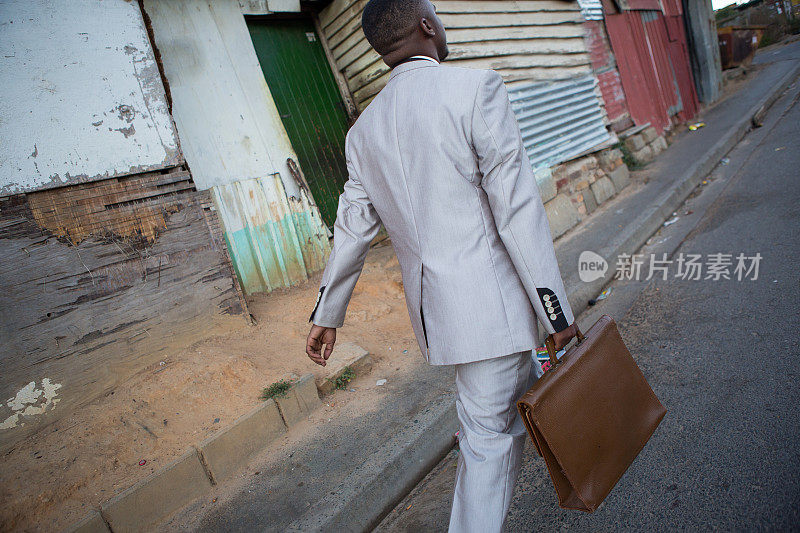 一个拿着公文包走路去上班的非洲人