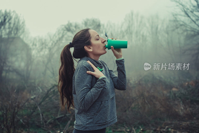 年轻的跑步者在绿色的钢桥上休息喝水