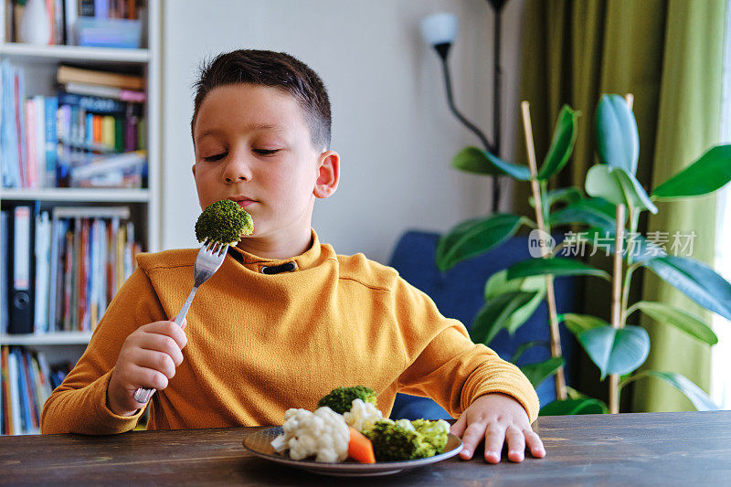 孩子对不得不吃蔬菜很不高兴。他的盘子里有许多蔬菜。他讨厌蔬菜。