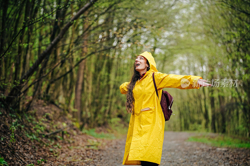 雨中穿着黄色雨衣的年轻女子