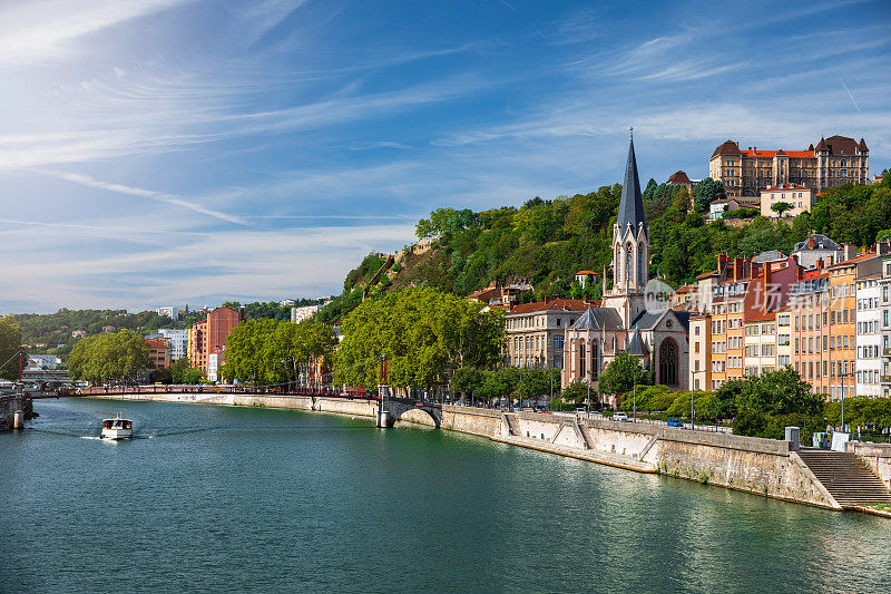 法国里昂市的Saone河岸，有圣乔治教堂和沿着五颜六色的公寓的观光船