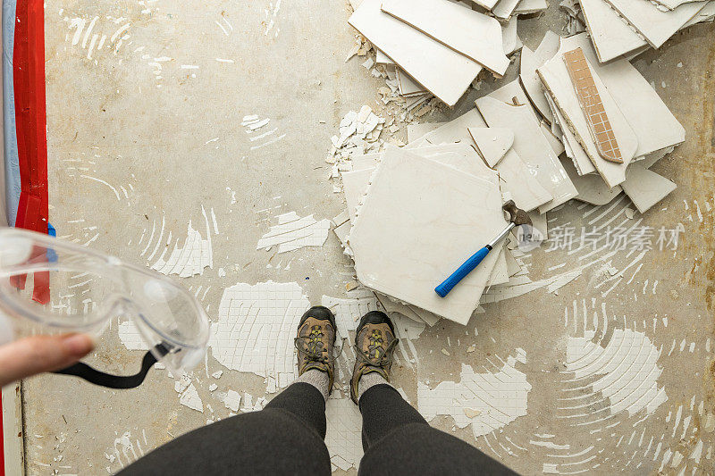 妇女在家居装修过程中俯视被拆除的瓷砖地板的个人视角
