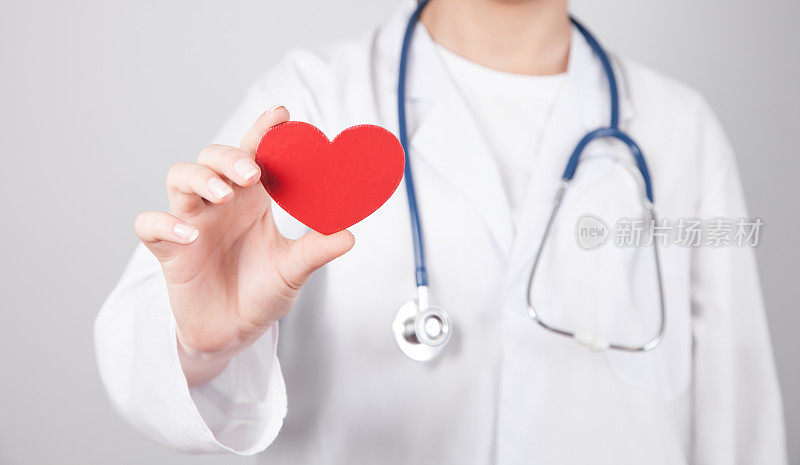医生用听诊器举着红色的心脏。