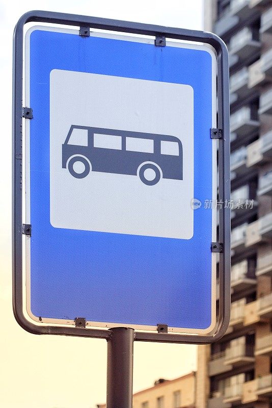 蓝色的公交站牌，背景是一座多层建筑。