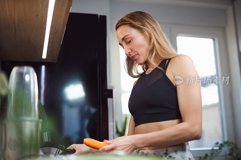 女人在厨房削胡萝卜，准备健康的零食