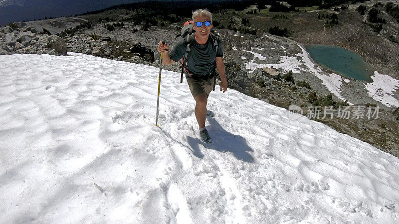 徒步旅行者沿着积雪的山坡跑下去