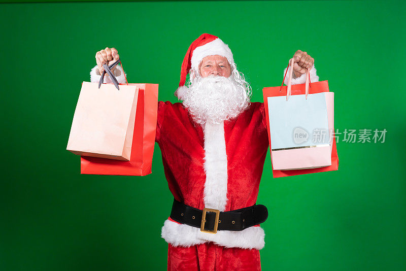 一个圣诞老人拿着一堆购物袋的照片