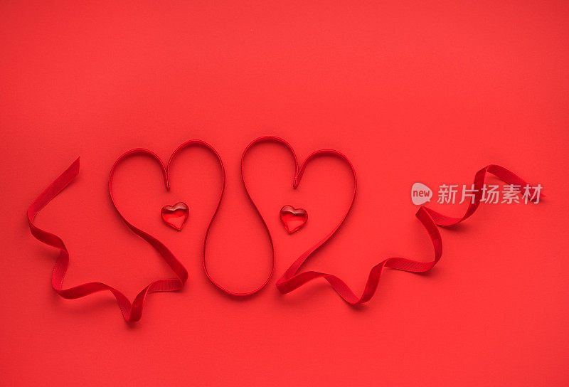 两颗用红丝带织成的红心。情人节贺卡的节日背景