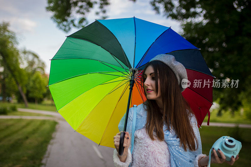 漂亮凉爽的女人带着五颜六色的雨伞在秋天的一天