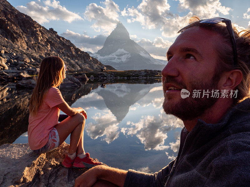 一对夫妇在湖边放松，凝视着日落时分的马特洪山