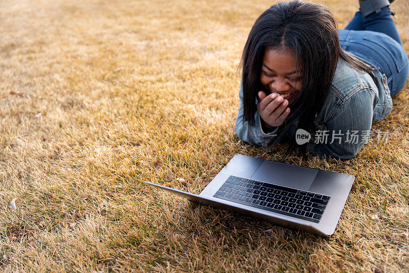 一个年轻的海地学生躺在草地上学习的特写