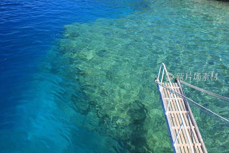 在Kekova岛的绿松石海洋底部可以看到古代遗迹，照片的右边可以看到一个木制的船梯