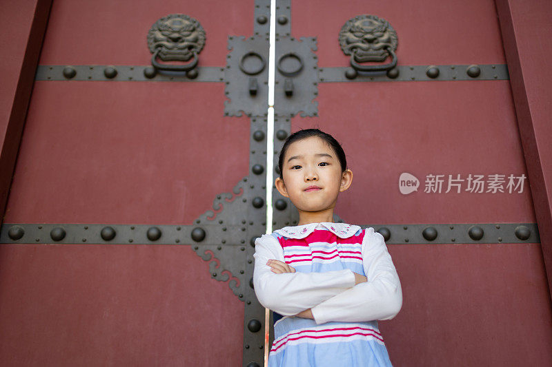 小女孩站在中国古典式大门前