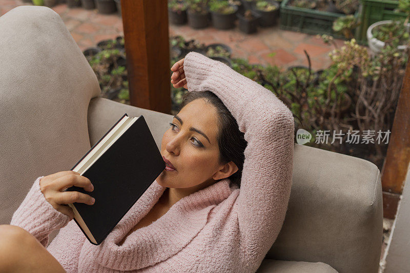 美丽很幸福的女人躺在家里的沙发上看书，在一个很安静的时刻