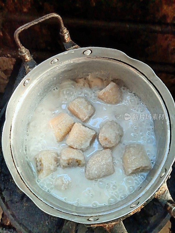 用椰子汁在炉子上煮香蕉，准备食物。