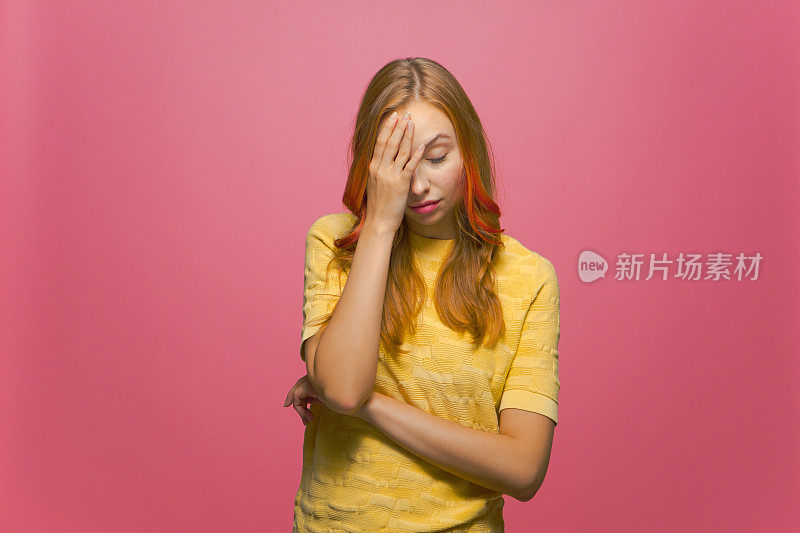 Facepalm指手势。年轻女子用手捂着脸，在粉红色的画室背景下感到羞愧和失望