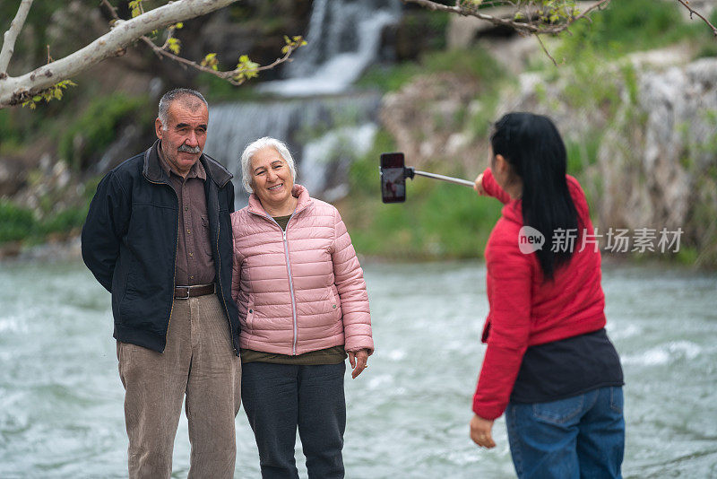 一个成熟的女人在河边拍摄她年长的父亲和母亲