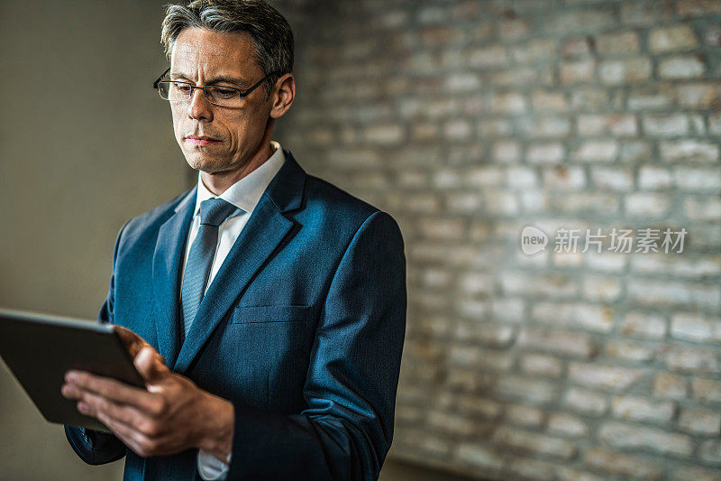 中年商人在办公室使用电子平板电脑。