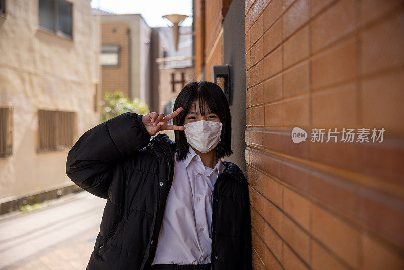 少女的肖像倚在墙上，做着和平的手势