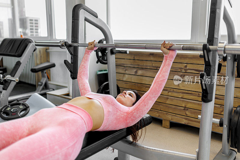快乐的运动员妇女训练的肖像侧向下拉重量锻炼机。女人握着宽握杆，