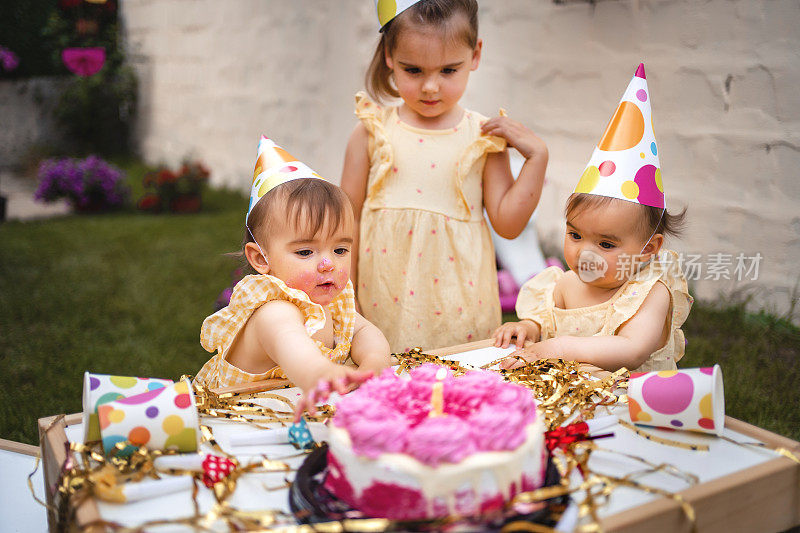 一对双胞胎姐妹和一个姐姐庆祝她们的第一个生日