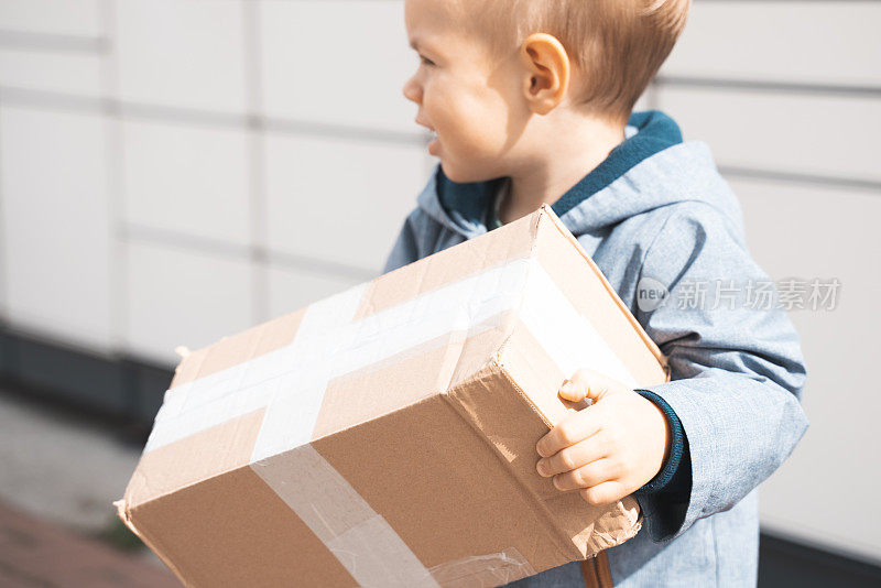 儿童包裹，男孩使用自助包裹终端机发送或接收包裹。包裹投递，带储物柜的取件点，小孩拿包裹，非接触式包裹投递