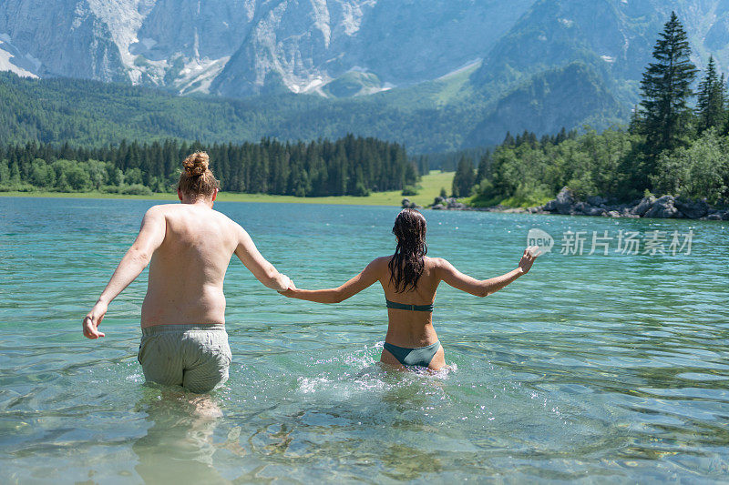 情侣牵着手跑进高山湖泊，欢天喜地