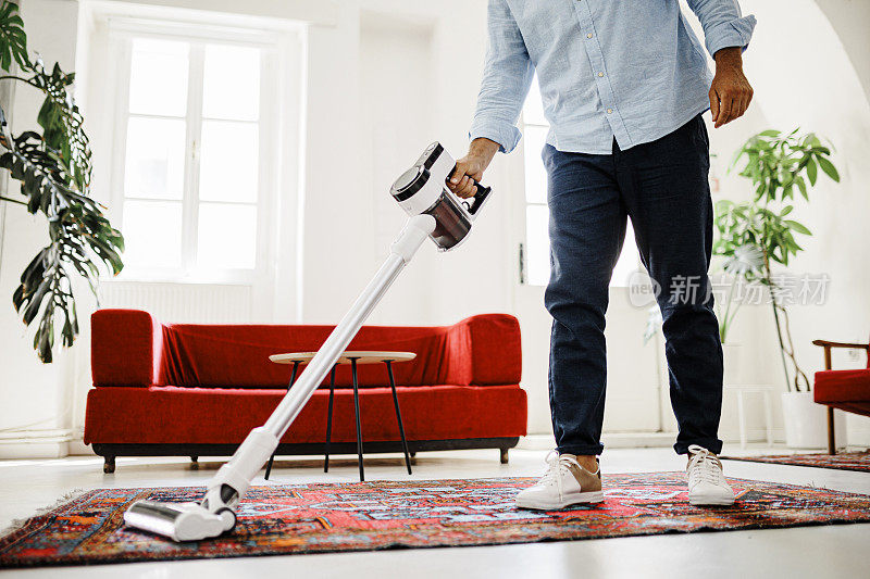 男人用无线吸尘器打扫房子的特写镜头