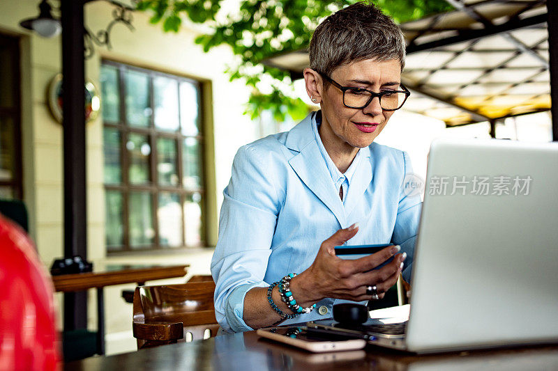 成熟女性坐在咖啡店用笔记本电脑网购