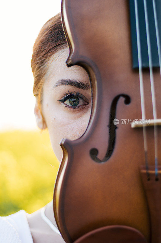 一头姜黄色头发，半边脸拉着小提琴的美丽年轻女子