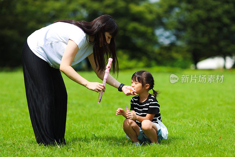 妈妈和女儿在公园里玩肥皂泡