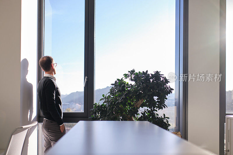 商业环境——商人站在办公室，看着窗外