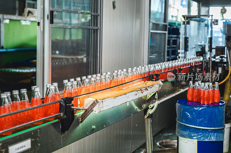饮料加工厂传送带上移动的瓶装果汁饮料生产线