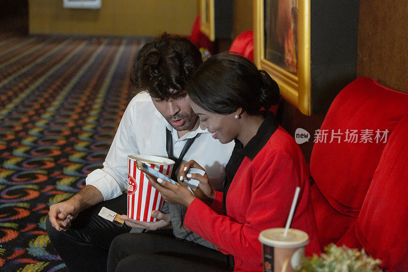 一对夫妇一边吃着爆米花，一边等着进电影院看电影