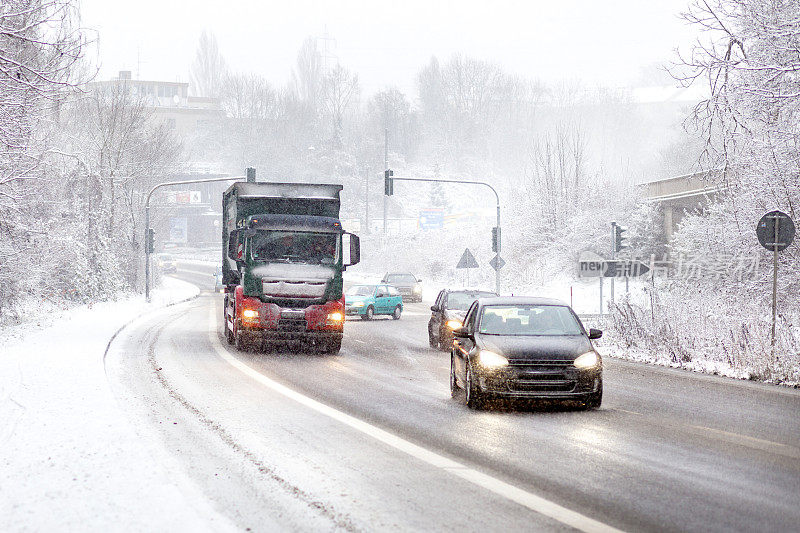 道路上的汽车和卡车在冬天的降雪中缓慢行驶