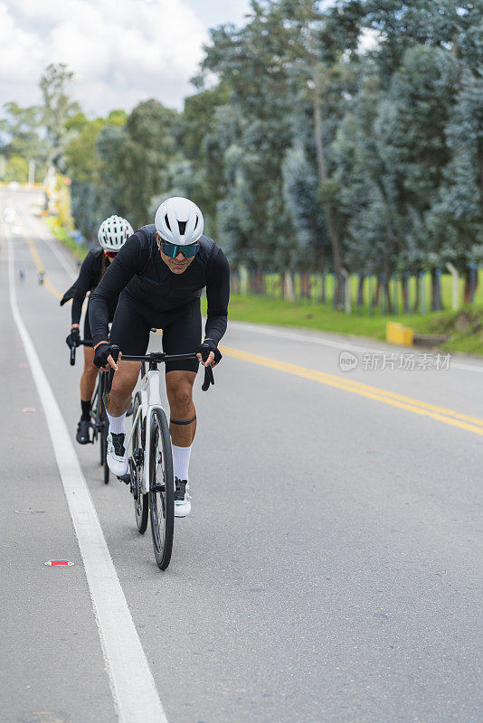 一对夫妇戴着安全帽和自行车眼镜，骑着白色自行车行驶在卡西卡-昆迪纳马卡的道路上