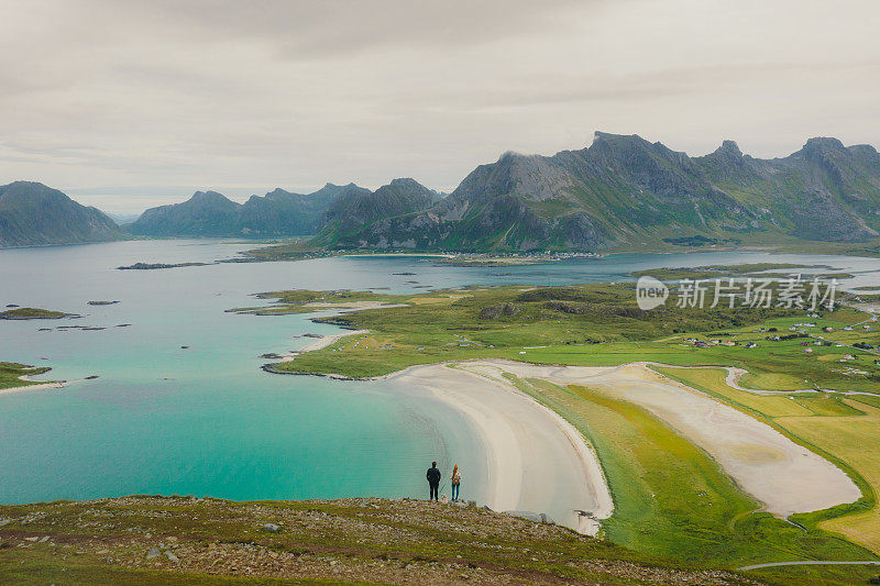 女人和男人从罗弗敦群岛的山顶俯瞰海洋和山脉的美景