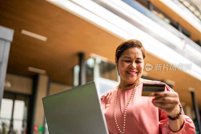 成熟女人在户外用笔记本电脑网购