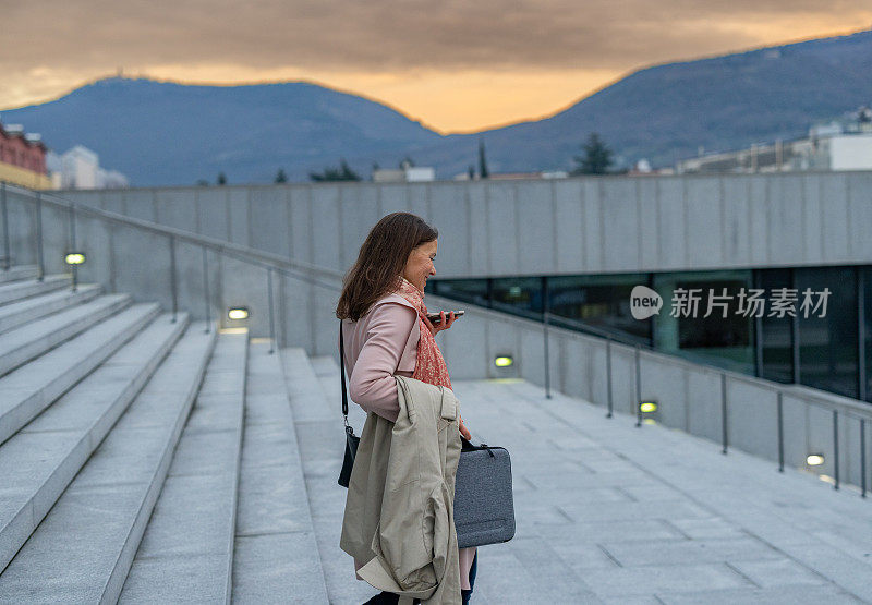 时髦的女商人在办公大楼外用手机发送语音信息