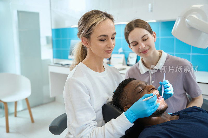 年轻护士协助女牙医进行口腔检查