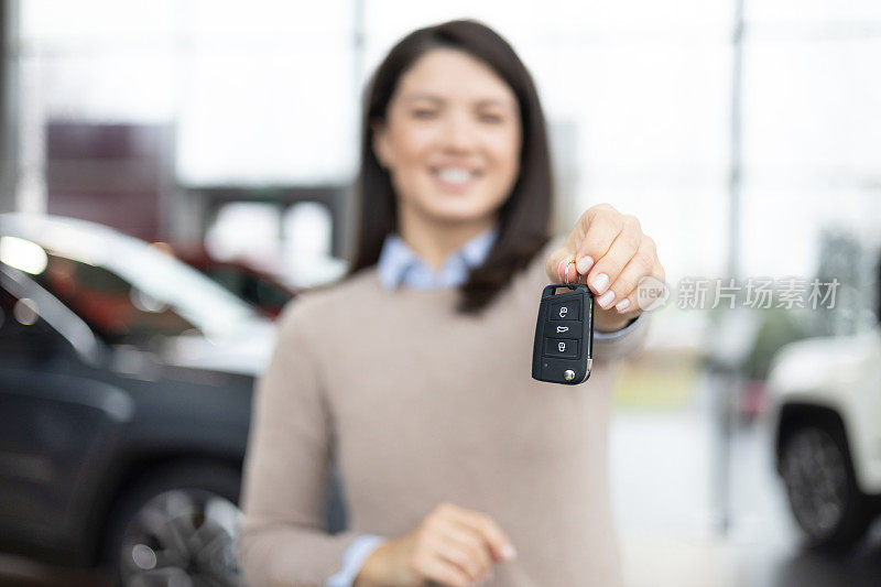 女士拿着车钥匙在展厅，顾客从经销商处购买新车