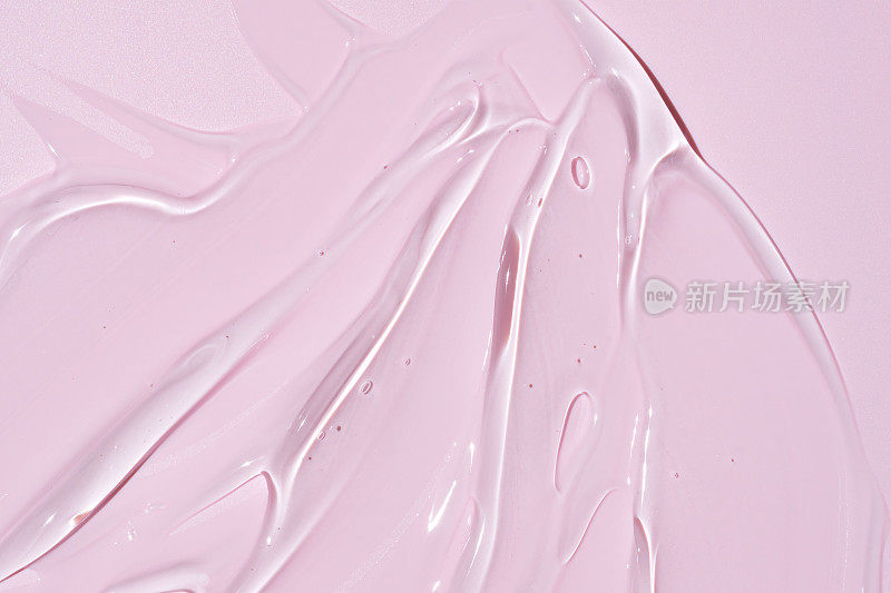 液体凝胶涂抹离子粉红色背景。美容化妆品污物，如纯透明芦荟乳液，面部啫喱精华液，洗面奶，沐浴露或洗发水俯视图