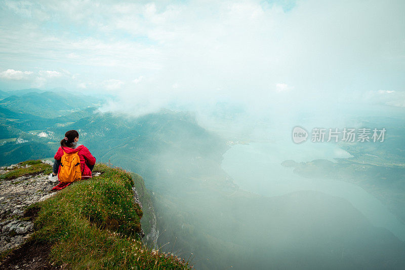 一位妇女站在山顶上欣赏山谷的景色。