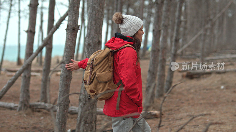 穿红衣服的女人在树林里徒步旅行。回归自然。