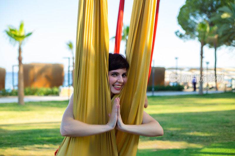 一名女子在织物上做空中体操时摆出瑜伽姿势